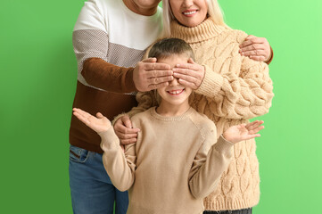 Wall Mural - Grandparents closing little boy's eyes on green background