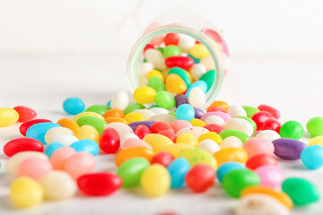 Wall Mural - Glass jar with different jelly beans on white background, closeup