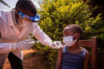 a doctor in africa vaccinates a child. doctor injects coronavirus vaccine to a kid in africa.