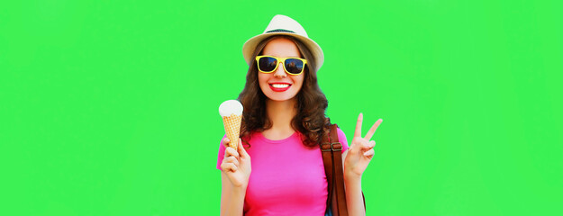 Portrait of happy smiling young woman with ice cream wearing summer straw hat on green background