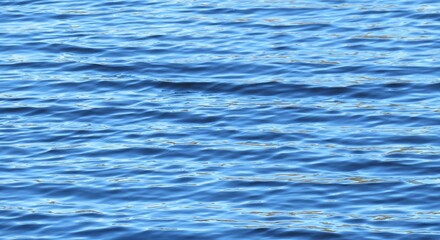 Panoramic view of light blue shining water surface with soft waves, natural background 