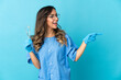© luismolinero - Woman dentist holding tools over isolated on blue background pointing finger to the side and presenting a product