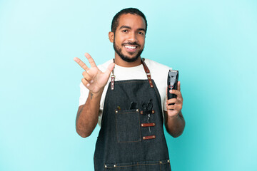 Wall Mural - Young hairdresser latin man isolated on blue background happy and counting three with fingers