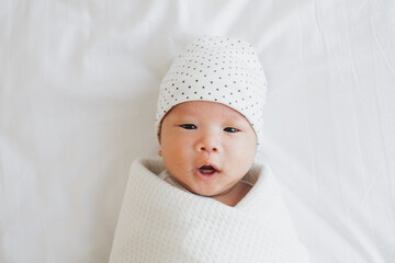 portrait asian newborn baby in white cloth on bed