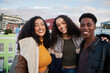 © StratfordProductions - Portrait of diverse group of multi-cultural young adults standing, smiling at camera on a rooftop terrace in city