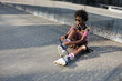 © Jelena - Young woman putting on rollerblades. Beautiful African woman with roller skates