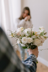 Wall Mural - Man in a shirt gives a bouquet to a young woman on a holiday on March 8. White roses in hand for your beloved