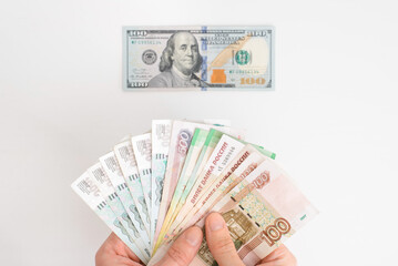 Financial crisis, economic problems, recession, currency inflation concept. Top view man holding stack of russian rubles banknotes against background of one hundred us dollars, close-up