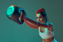 Portrait Of Sportive Woman Workout, Doing Exercises With Sports Equipment Isolated On Green Studio Background In Neon Light. Sport, Action, Fitness, Youth Concept.