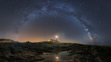 A Beautiful Landscape View Of Half Cloudy Circle On A Lighthouse Reflecting On Water At Night