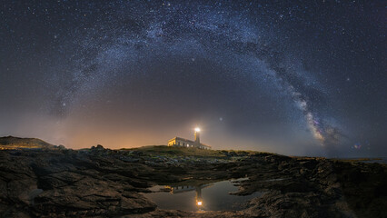 Wall Mural - A beautiful landscape view of half cloudy circle on a lighthouse reflecting on water at night