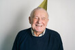 © ADDICTIVE STOCK - Cheerful elderly man in party hat in studio