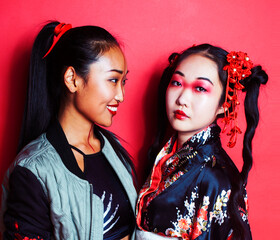 Poster - two pretty geisha friends: modern asian woman and traditional wearing kimono posing cheerful on red background