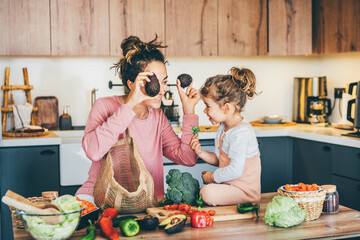 Woman having fun with her daughter while preparing food in the kitchen.