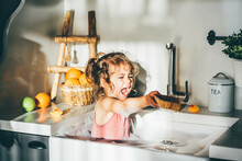 Funny Happy Baby Girl Playing In A Kitchen Sink.