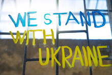 A dirty barred window on which is drawn in blue and yellow colours. We stand with Ukraine.