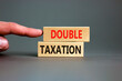 Double taxation symbol. Concept words Double taxation on wooden blocks on a beautiful grey table grey background. Businessman hand. Business tax and double taxation concept, copy space.