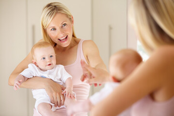 that cute little girl is you.... a cute baby girl looking at herself in the mirror while her mom poi