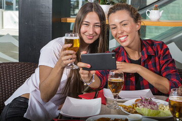 2 young women eating in a restaurant and taking a selfie