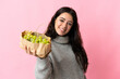 © luismolinero - Young caucasian woman holding a grapes isolated on blue background with happy expression