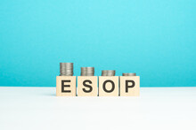 Wooden Blocks With Text ESOP And Coins On Wooden Table. Copy Space. Blue Background