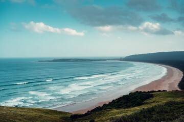 Panoramic view of blue ocean waves and a pink sand beach