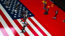 The Concept Of The Economic And Political Crisis Between The United States And China, Toy Soldiers Attacking Each Other Against The Background Of National Flags.