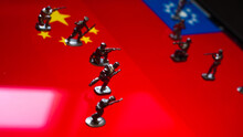 The Concept Of The Economic And Political Crisis Between China And Taiwan, Toy Soldiers Attacking Each Other Against The Background Of National Flags.