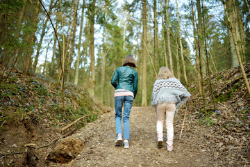 Adorable young sisters having fun during a hike in the woods on beautiful sunny spring day. Active family leisure with kids.