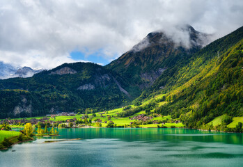 Wall Mural - lungern, canton of obwalden, switzerland. a view of rural homes in a green meadow. a lake in a mount