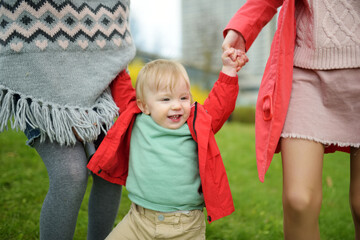 Poster - Two big sisters and their toddler brother having fun outdoors. Two young girls holding their baby boy sibling on sunny spring day. Kids with large age gap.