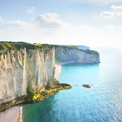 Picturesque panoramic aerial view of the Etretat white cliffs at sunset. Dramatic sky, azure water. Summer vacations in Normandy, France. Travel destinations, national landmark, sightseeing, history