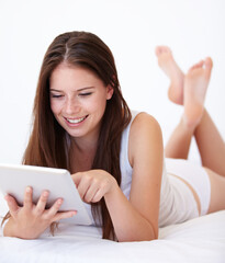 Canvas Print - Going online from the comfort of her bed. A gorgeous young woman working on her digital tablet.