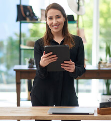 Wall Mural - Be a smart business owner. Portrait of a young business owner using a digital tablet in her clothing store.