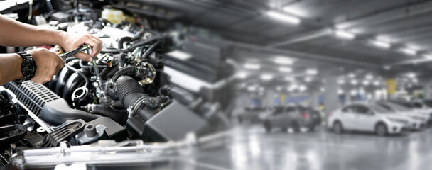 Service concept panorama photo: The serviceman hold the car disassembly wrench in the engine compartment of the car and car parking area in the car service center to wait for service