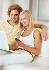 Wall Mural - Searching for something for their new house. A happy young couple doing their online banking from the comfort of their couch.