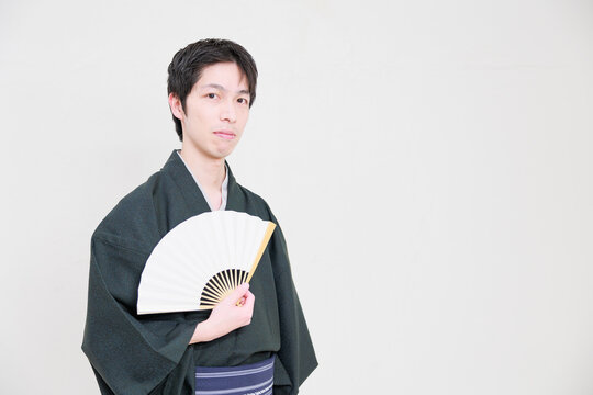 開いた扇子を持つ着物を着た日本人男性