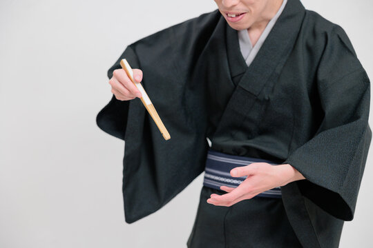 扇子を使って食べる物まねをする落語家