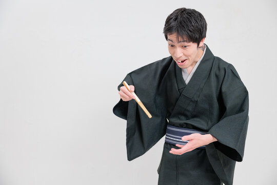 扇子を使って食べる物まねをする落語家