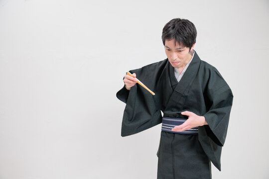 扇子を使って食べる物まねをする落語家