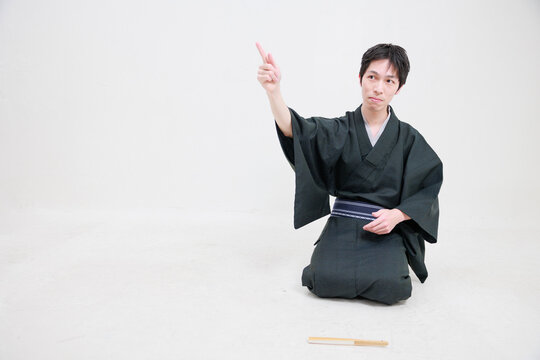 着物を着た男性が正座をして空間を指さす