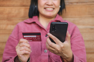 Poster - woman shopping online with credit card at coffee shop in outdoor.close up hand holding smartphone