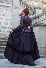 Sticker - Full length portrait of red-haired woman wearing a historical victorian gown costume, walking around beautiful location with  Gothic stone architecture.