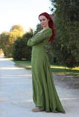 Canvas Print - Full length portrait of red haired woman wearing a  beautiful  green medieval fantasy gown. Posing with gestural hands on a enchanted forest background.