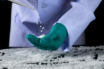 Employees wearing green gloves work with plastic beads.close-up shot of polymer pallet. Products from petrochemical plants. Scientists experiment with reducing or reusing plastic.