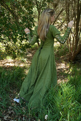 Poster - Full length portrait of blondewoman wearing a  beautiful  green medieval fantasy gown. Posing with gestural hands in a enchanted forest background.