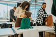 © Maskot - Multiracial students packing backpack in classroom at community college