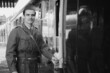 Handsome male British soldier in WW2 vintage uniform at train station next to train, looking pensive