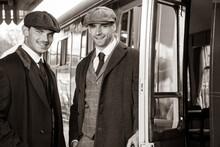 Handsome English Gangsters Standing Next To Train At Railway Station, Laughing, With Train In Background