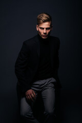 Canvas Print - Formally dressed man with sharp jawline in his 20's posing in a studio in front of a black background.